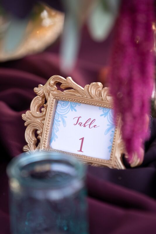 Table number in a gold filigree frame on a burgundy table cloth