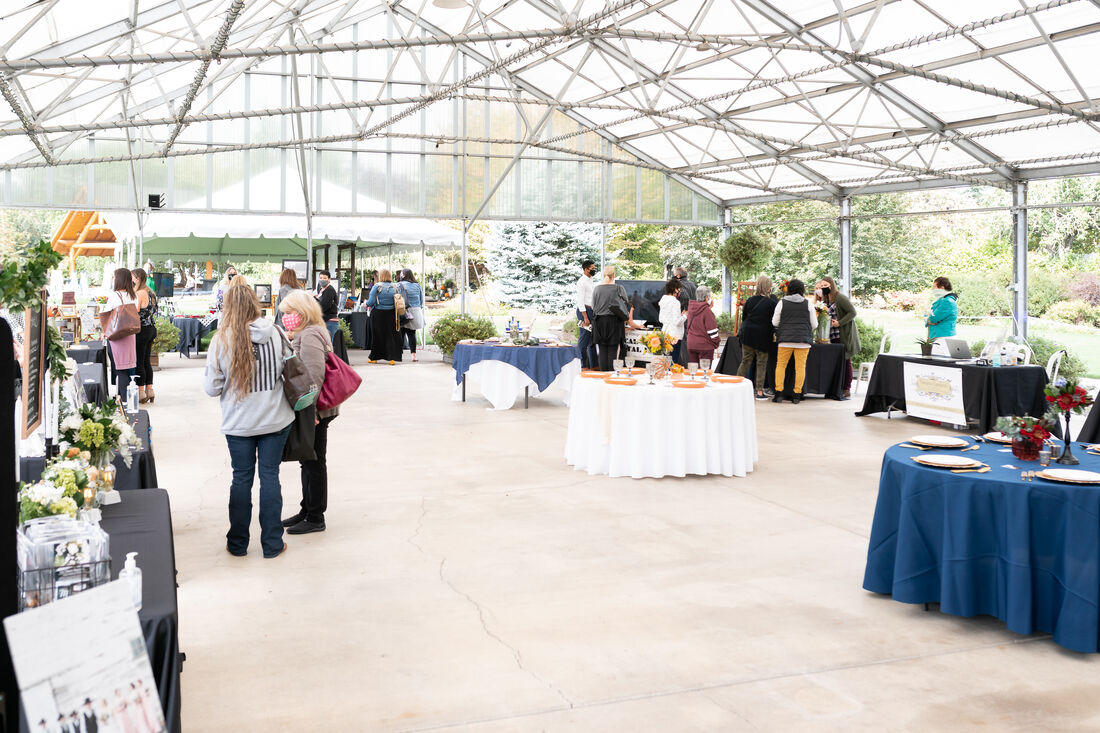 Guests meeting with vendors at the 2020 Willamette Valley Wedding Professionals Wedding Showcase at Log House Garden at Willow Lake.
